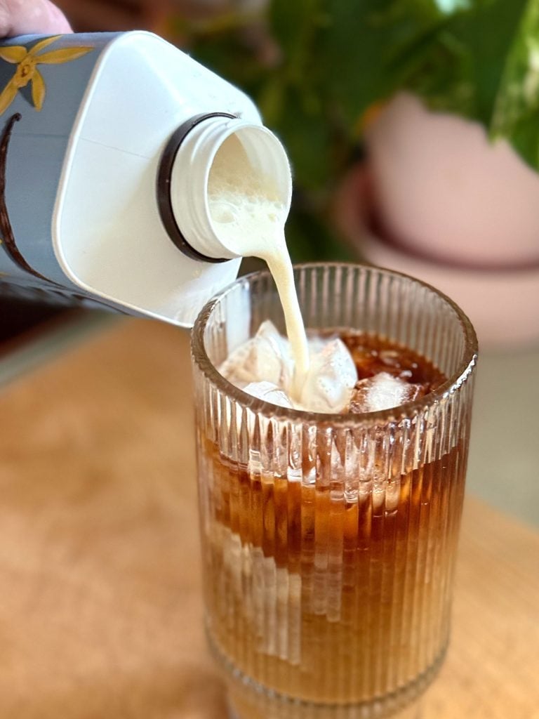 cold-brew-maker-pouring-creamer-768x1024-1 Pouring Creamer Into Glass of Iced Cold Brew Coffee Made At Home