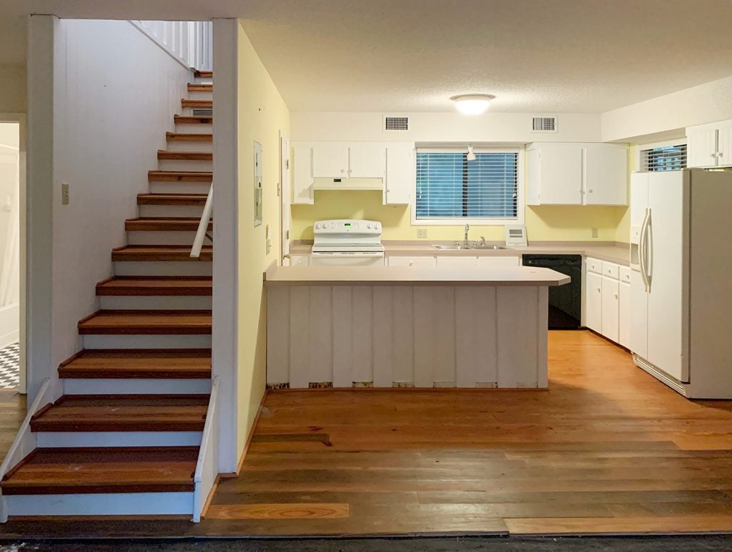 Before photo of kitchen with yellow walls and stairs