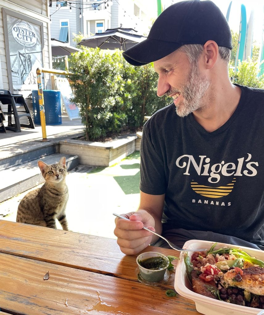 john-sitting-with-cat-at-lunch-856x1024-1 John Eating Lunch Next To Boy Cat At Patio Restaurant
