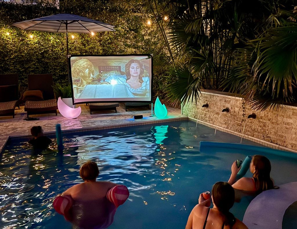 outdoor-movie-night-four-people-watching-1024x792-1 People Watching Movie on Outdoor Screen From Pool
