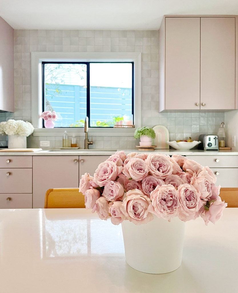 Pink Roses On Breakfast Table In Kitchen With Mauve Cabinets And Tile Backsplash