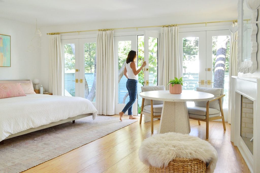 beachy-bedroom-wall-of-doors-open-sherry-1024x681-1 Woman Walking Through Wall Of French Doors In Bright Beachy Bedroom
