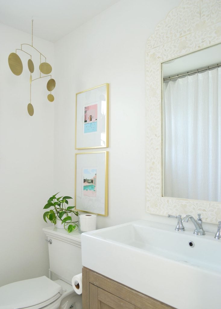 downsized-items-bathroom-733x1024-2 White bathroom with inlay mirror gold picture frames and brass mobile