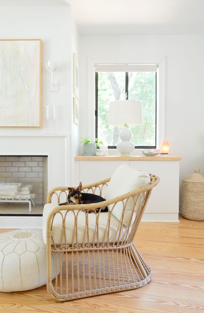 downsized-items-bedroom-fireplace-667x1024-1 Wicker chair in bedroom with dog sitting on it in front of fireplace