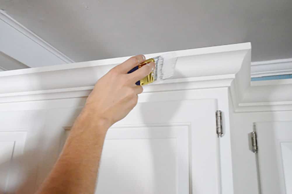 kitchen-crown-painting Painting crown molding on a kitchen cabinet with a short handled paint brush