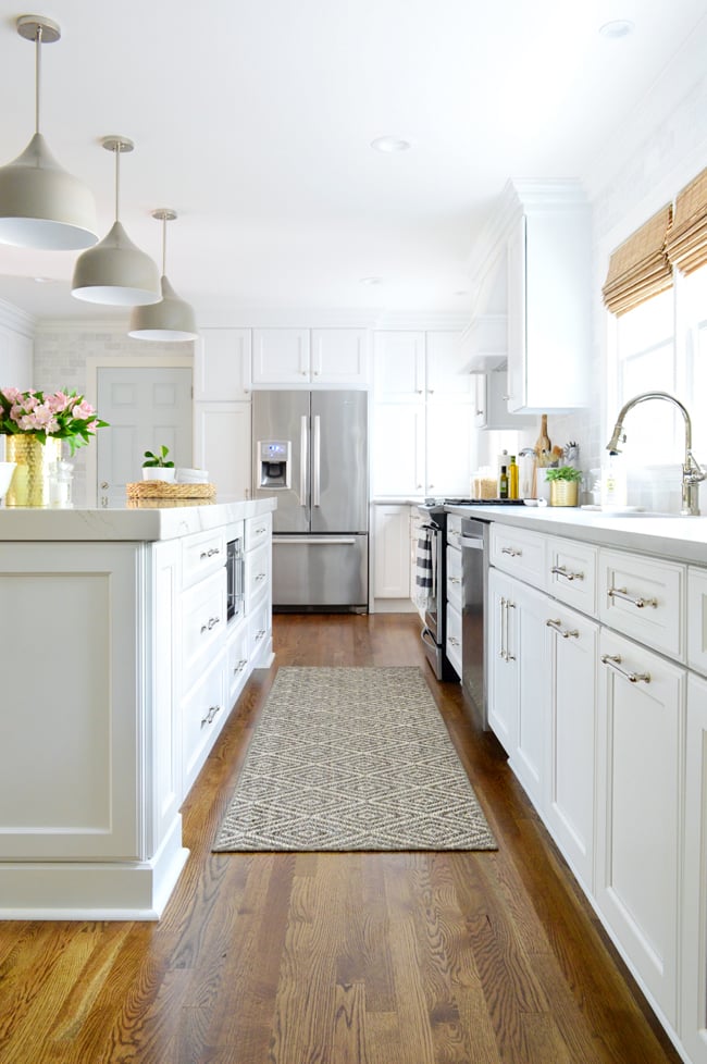 kitchen-remodel-final-down-aisle-to-fridge-650 White kitchen with island and quartz countertops and gray light fixtures