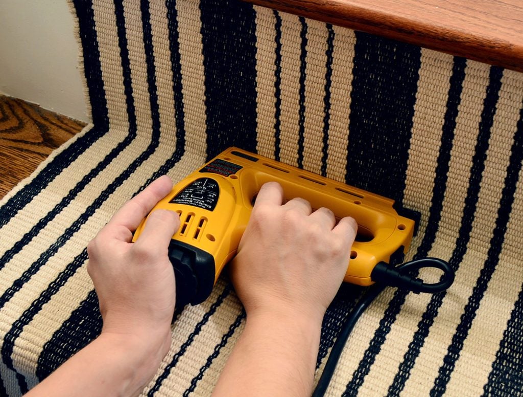 nailing-stair-runner-at-bottom-1024x776-1 Electric staple gun securing runner to the bottom of the top first risier
