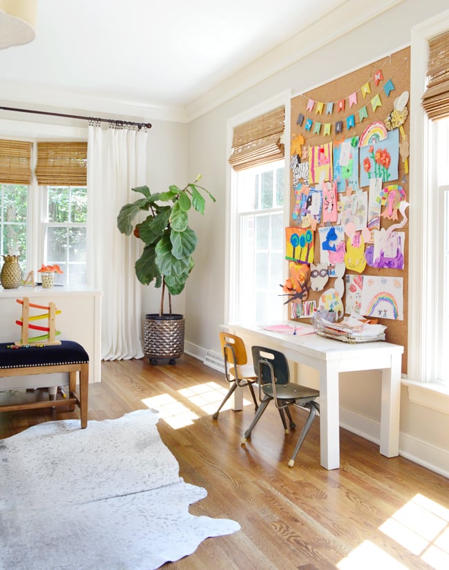 neutral-office-kids-cork-board-art-desk-650 Office space with a kids desk with windows and a wall sized cork board above the kids desk