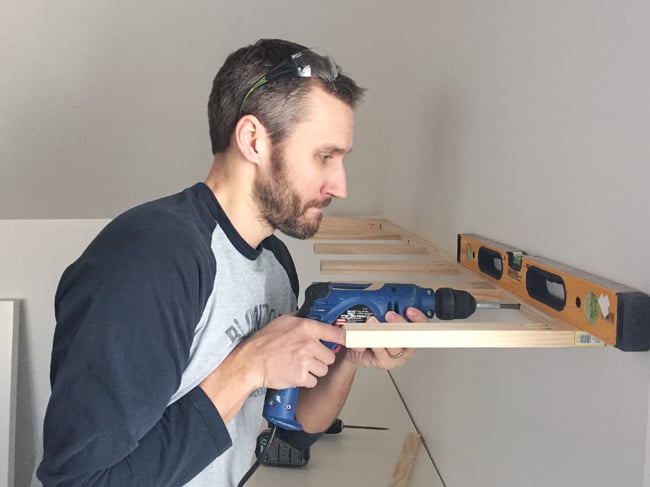 bonusbuilts-uppers-johnscrewing attaching brace piece for white floating shelves using a power drill driver and level