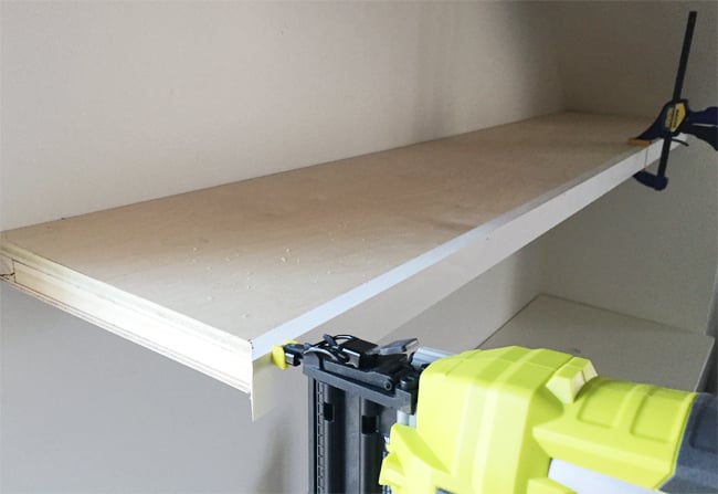 bonusbuilts-uppers-nailingfaces A Ryobi power nailer attaching face pieces of 1x2 pine wood board to thin white floating shelves in bonus room