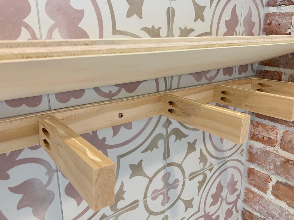 duplex-kitchen-shelves-adding-top-1024x768-2 Plywood Top Being Lowered Onto Wooden Support Bracket For DIY Floating Shelves