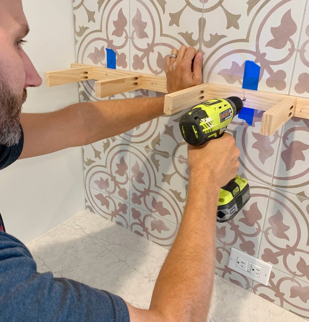 duplex-kitchen-shelves-drilling-marking-hole-983x1024-1 Man Drilling Through Shelf Support Bracket To Mark Locations On Tile