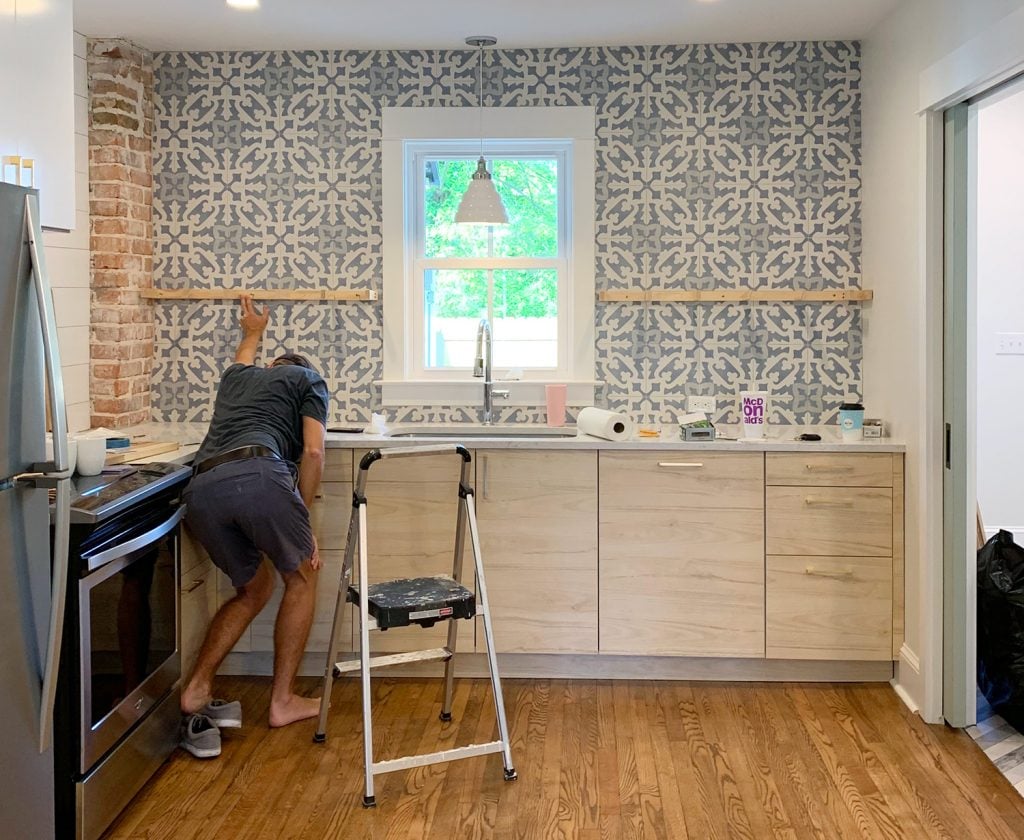 duplex-kitchen-shelves-john-holding-up-bracket-1024x840-1 Man Crouching While Holding Kitchen Floating Shelf Bracket Against Tile For Placement