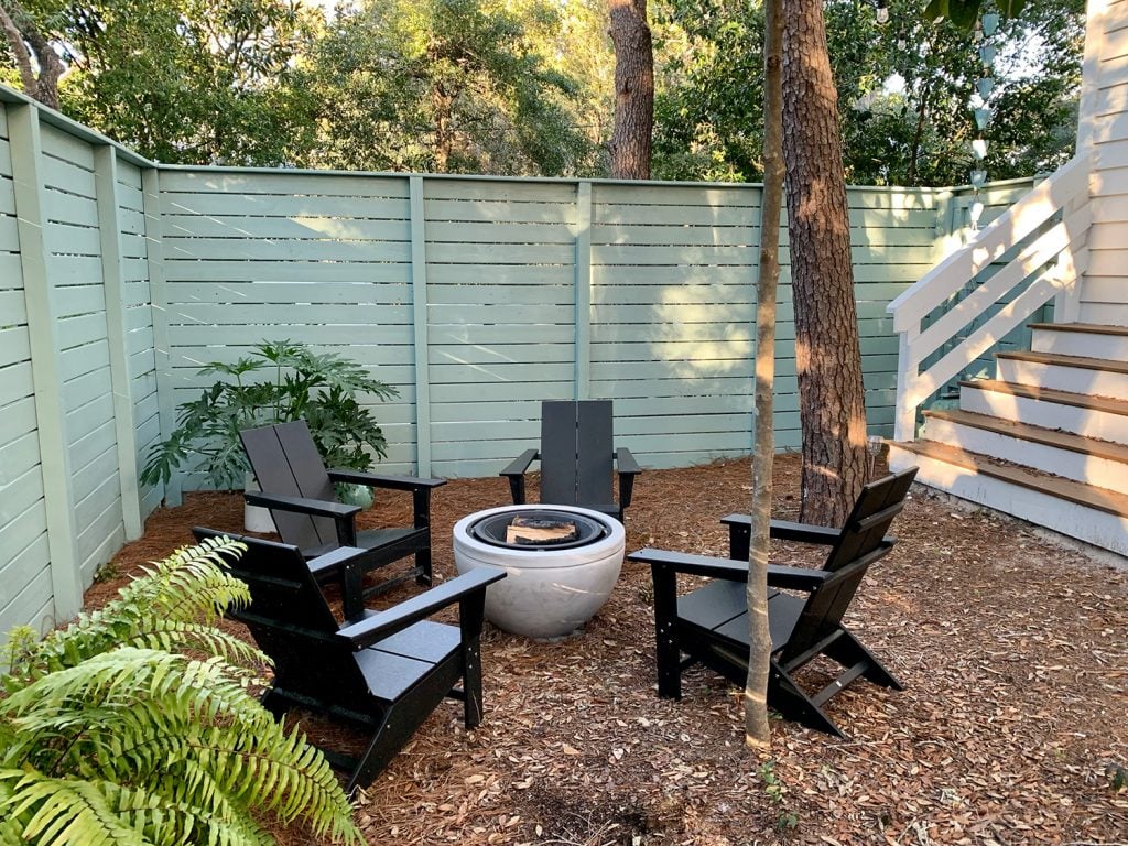 firepit-area-horizontal-side-shot-1024x768-1 Painted fenced side yard with black Adirondack chairs around fire pit with potted plants