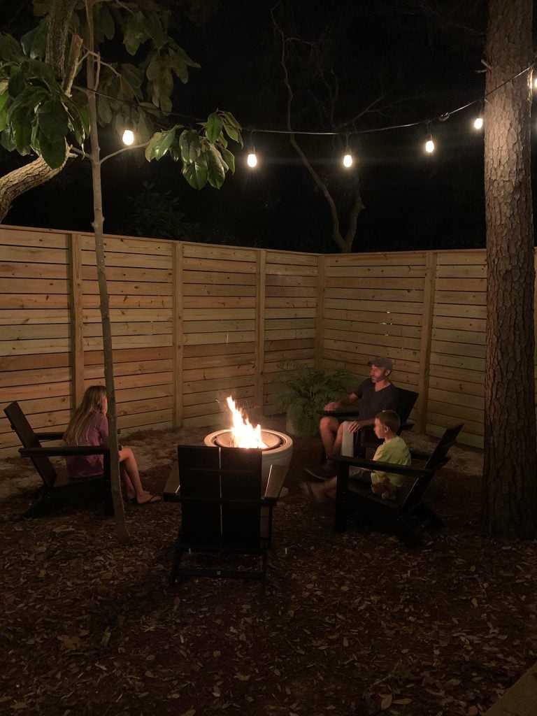 firepit-area-in-use-before-fence-painted-768x1024-1 Family sitting around fire pit with unpainted fence