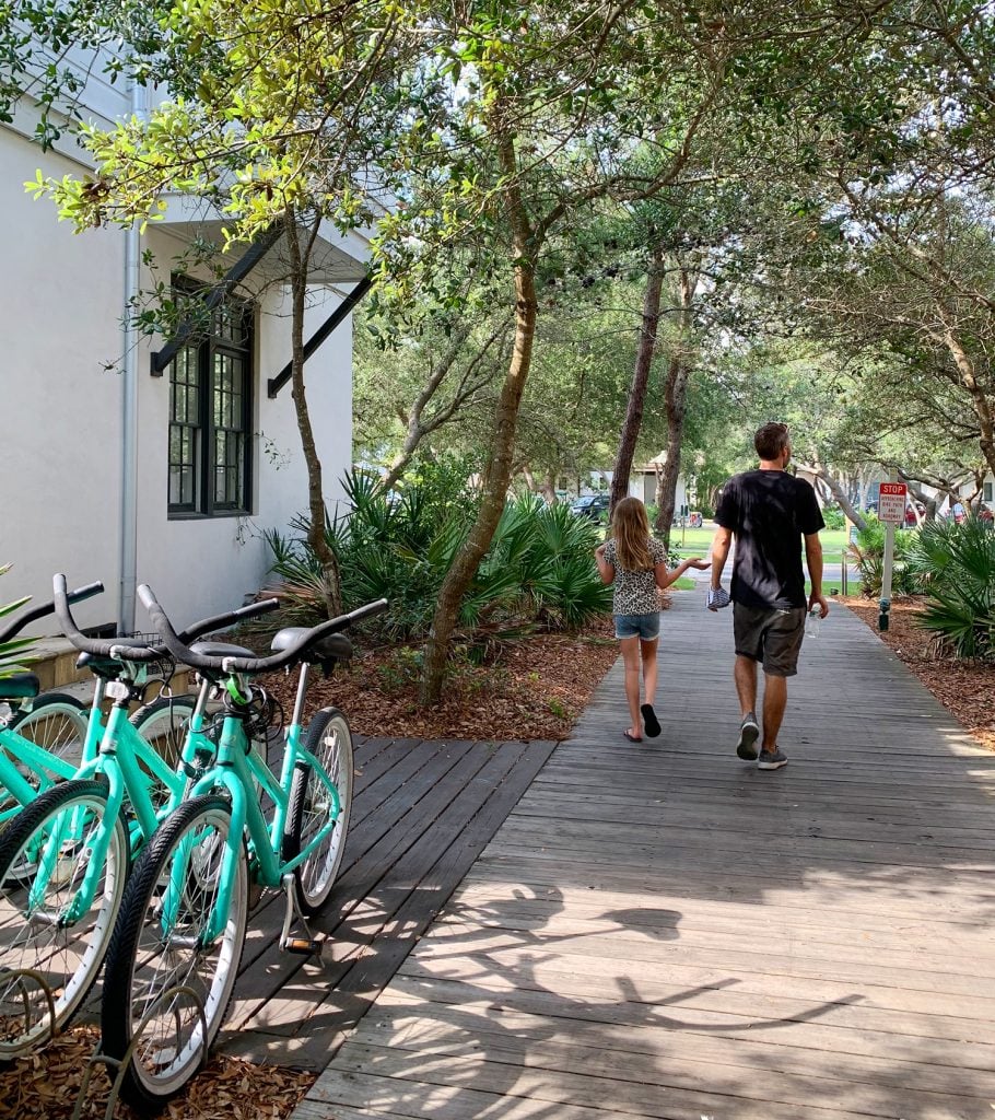 florida-downsizing-walking-bikes-910x1024-1 John and daughter walking on wooded walkway next to bikes