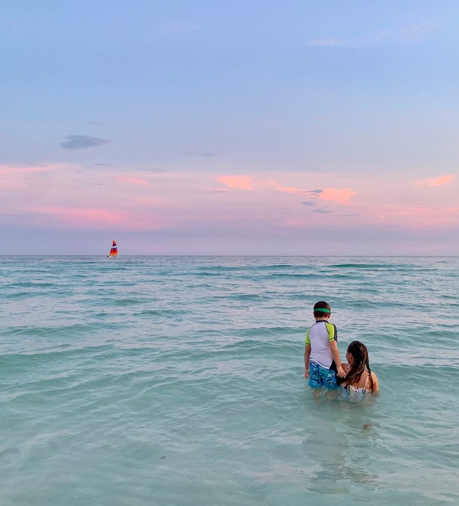 florida-gulf-of-mexico-sunset-beach-930x1024-1 Kids playing in Gulf of Mexico at sunset with sailboat in background