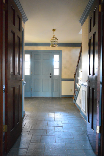 foyer-before1 before photo of 1980s entryway foyer with williamsburg blue trim, dark wood molding, wallpaper, and discolored slate tile floor