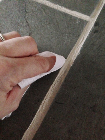grout5 wiping edge of PolyBlend Grout Renew application to dirty grout with clean paper towel