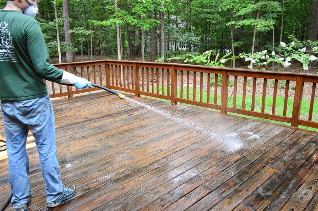 how-to-strip-a-deck-john-spraying-cleaner-off-1024x681-1 John rinsing deck cleaner off with garden hose