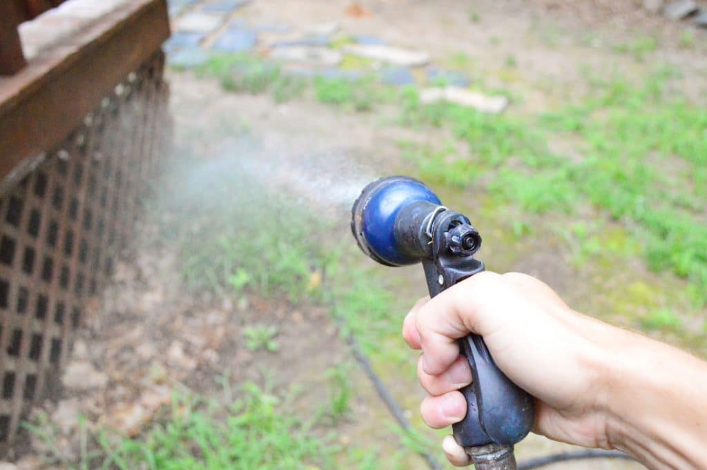 how-to-strip-a-deck-spray-landscaping-1024x681-1 Hose spraying grass and plants near deck