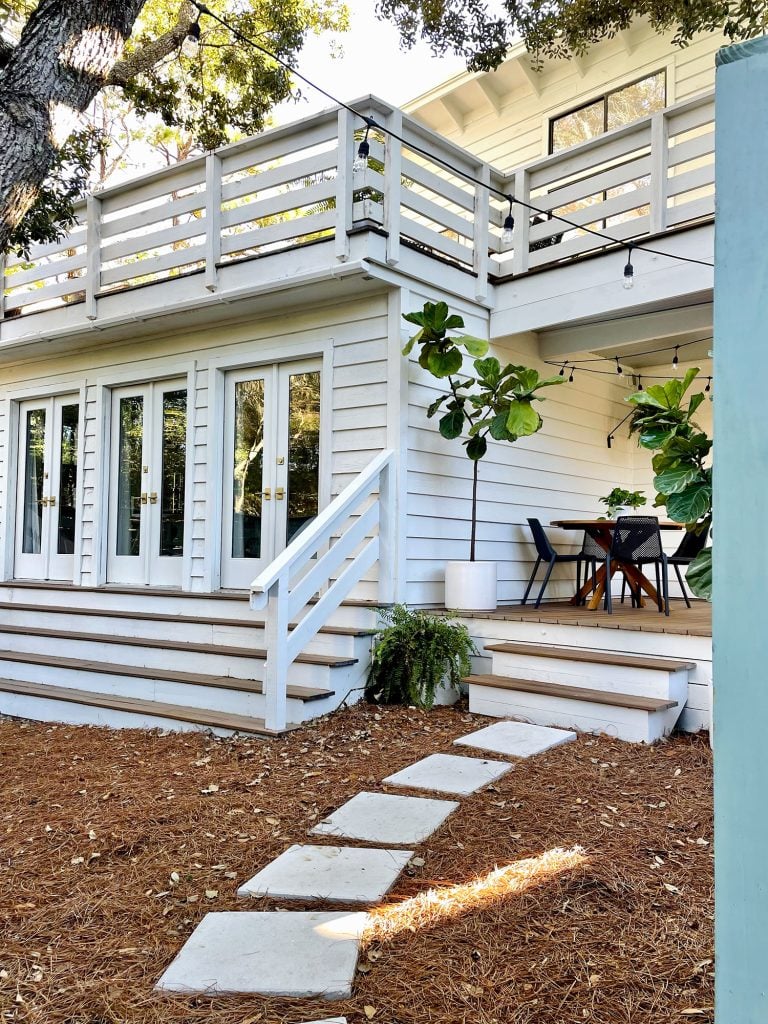 kitchen-porch-after-from-gate-768x1024-1 Angled view through fence gate at side porch yard area with doors to bedroom