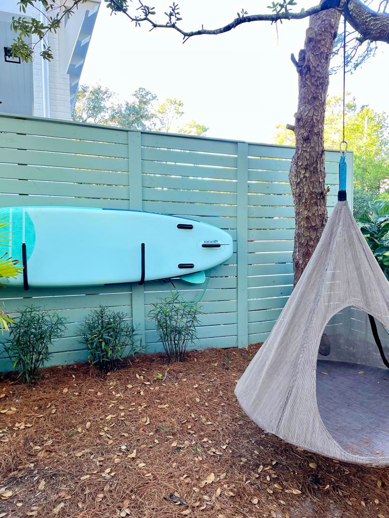 kitchen-porch-swing-and-paddleboard-768x1024-1 Side yard area with paddleboard stored on fence with hanging tent swing