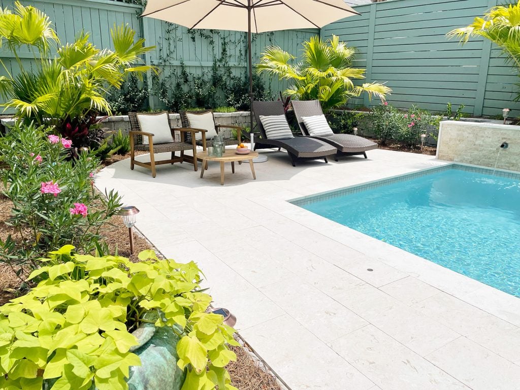 pool-post-after-plants-around-perimeter-and-sitting-area-1024x768-1 Backyard pool with sitting area under umbrella surrounded by tropical plants