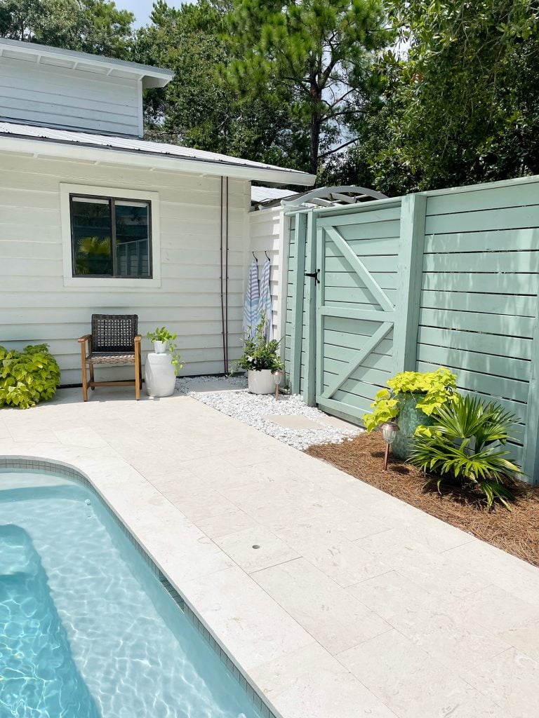 pool-post-corner-with-outdoor-shower-gate-fence-teal-water-along-ledge-768x1024-1 Horizontal slat gray green wood fence around pool area with gate near house