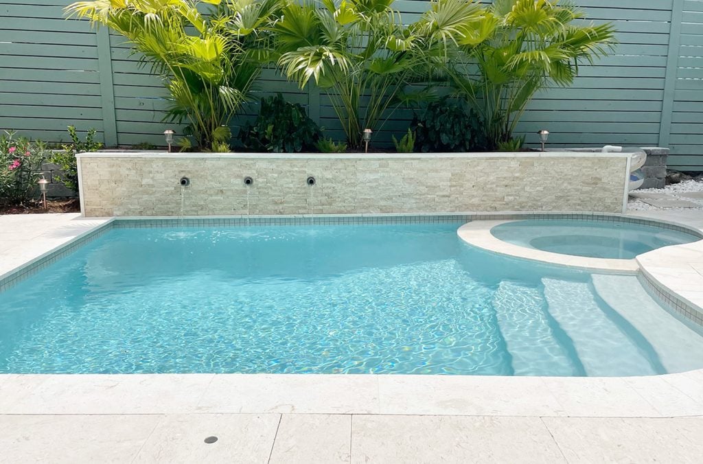 pool-post-horizontal-full-long-side-of-pool-with-wall-1024x676-1 Small freeform pool with accent stone tile retaining wall flanked by gray block retaining wall