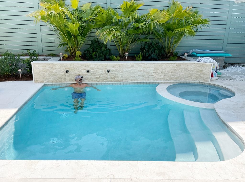 pool-post-john-with-fountains-1024x763-1 John in small freeform pool against stone accent retaining wall under palm plants