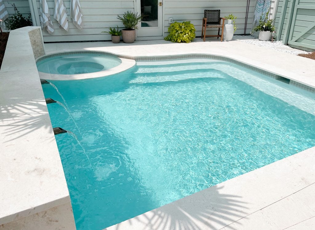 pool-post-overhead-water-color-always-changing-palm-shadows-1024x748-1 Angled view of small freeform pool with stairs at one end and bench across one end showing Ivory DiamondBrite plaster