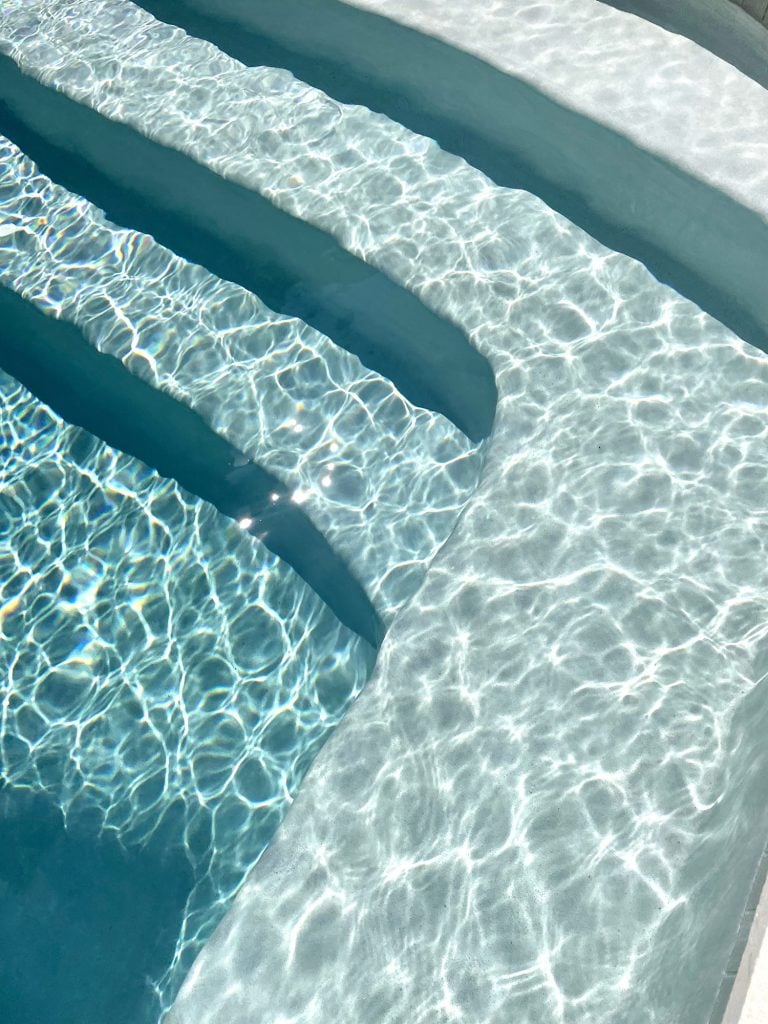 pool-post-plaster-color-water-reflection-photo-768x1024-1 Detail photo of pool color getting darker as water gets deeper at steps Ivory DiamondBrite