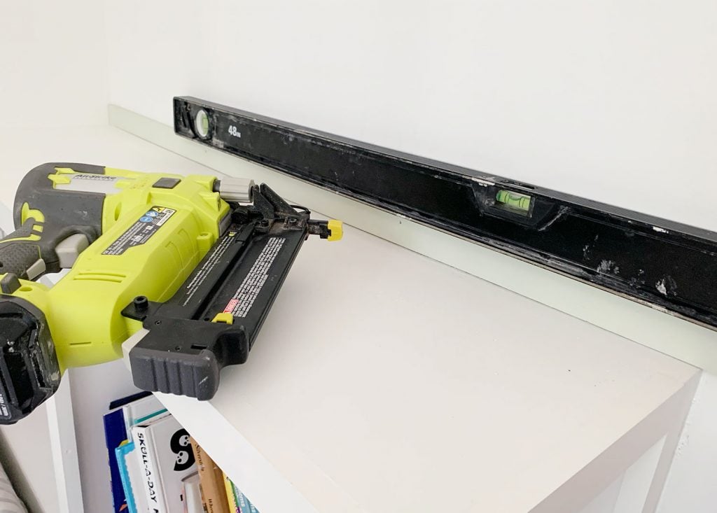 rainbow-stripe-wall-leveling-first-piece-1024x733-1 Nail Gun Next To First Strip Of Wood Lattice Attached To Wall With Level