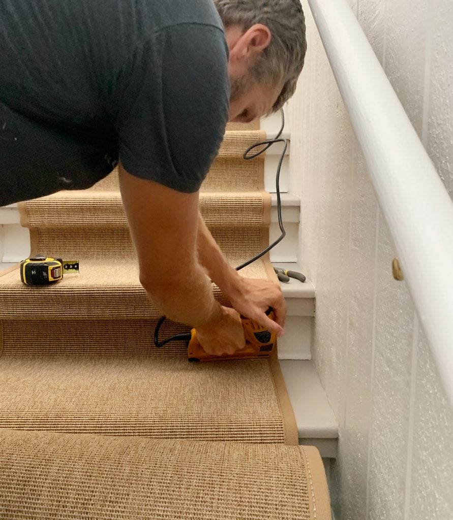 sisal-stair-runner-john-nailing-at-base-891x1024-1 John Using Electric Staple Gun To Drive Staple Into Bottom Corner Of Stair To Secure Sisal Runner